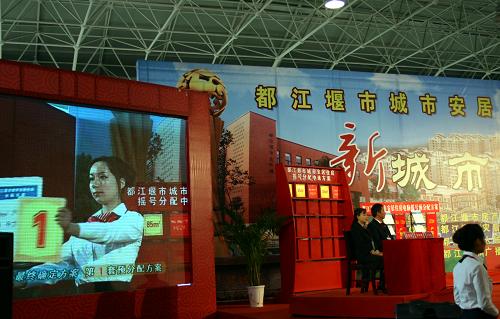 12月8日,在搖號分配現(xiàn)場,禮儀人員在向現(xiàn)場觀眾展示其中一種戶型的中選方案。當(dāng)日,四川省都江堰市完成最后一批次4556套災(zāi)后重建城市安居住房公開搖號分配。這標(biāo)志著由政府統(tǒng)規(guī)統(tǒng)建的18058套安居住房完成分配。今年年底以前,都江堰災(zāi)區(qū)所有城市安居住房將實現(xiàn)全部移交。
