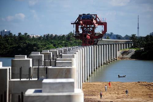 8月22日,建設(shè)者在海南東環(huán)鐵路萬泉河大橋建設(shè)工地架設(shè)箱梁。這座海南東環(huán)鐵路的必經(jīng)之路、橫跨萬泉河的大橋全長(zhǎng)3974米,共需架設(shè)122片箱梁,目前已架設(shè)60片。施工單位計(jì)劃今年11月10日前完成東環(huán)鐵路瓊海境內(nèi)路段全部大型橋梁箱梁的架設(shè)任務(wù),以保障東環(huán)鐵路建設(shè)順利進(jìn)行。東環(huán)鐵路是海南省與鐵道部聯(lián)合投資的城際軌道交通工程,總投資達(dá)202億元,項(xiàng)目于2007年9月開工,計(jì)劃2010年年底建成開通運(yùn)營(yíng)。 新華社發(fā)(蒙鐘德 攝)
