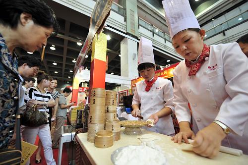 9月17日,觀眾在中華老字號精品博覽會上觀看天津“狗不理”包子的制作過程。新華社發(fā)