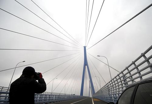 11月17日,一名記者在拍攝剛剛建成的金塘跨海大橋。該橋連接舟山金塘島和大陸,全長26.54公里,其中跨海大橋長18.27公里,該橋投資約77億元,是舟山5座跨海大陸連島大橋中投資最大、跨度最長的大橋。新華社記者 徐昱 攝