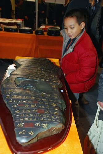 11月29日,在北京文博會上,一件刻有蘭亭序的苜卻硯吸引小朋友駐足觀賞。新華社發(fā)(韓路 攝)