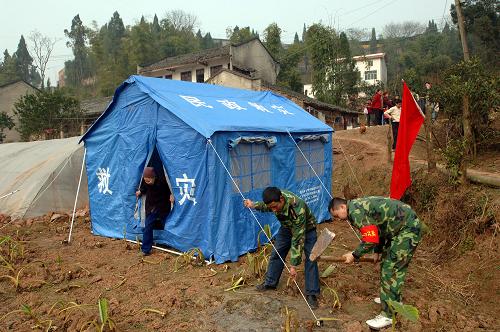 1月31日,在重慶潼南縣雙江鎮(zhèn)老關(guān)村,當?shù)孛癖鵀槭転?zāi)村民搭建帳篷時,72歲的村民廖秀云在查看帳篷。新華社記者 陳誠 攝