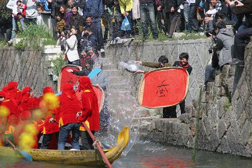 4月5日,嫂子龍舟隊隊員用船槳將河水潑向蠶農(nóng)手舉的蠶匾。新華社發(fā)(倪立芳 攝)