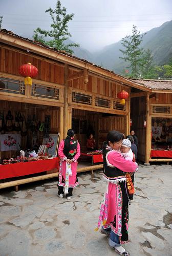 5月7日,四川省北川縣擂鼓鎮(zhèn)貓兒石村吉娜羌寨的繡女在羌繡工藝品店鋪前休息。她們身上鮮艷的羌族服飾都是自己一針一線繡制而成。 新華社記者 陳凱 攝