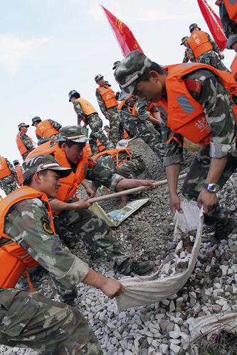 6月25日,武警官兵正在奮力裝運沙石。受贛江第二次洪峰影響,江西省吉安市新干縣境內(nèi)贛東、贛西大堤超警戒水位1.34米,嚴(yán)重危及周邊地區(qū)近百萬群眾的生命財產(chǎn)安全。武警江西總隊吉安市支隊迅即出動官兵1000余人次,奔赴新干縣加固堤壩、堵塞管涌。經(jīng)過近10個小時的奮戰(zhàn),官兵共堵塞管涌6處,抬運沙石8000余袋,構(gòu)筑圍堰100余米,大堤的安全得到進(jìn)一步穩(wěn)固。新華社發(fā)(戴慶明 攝)