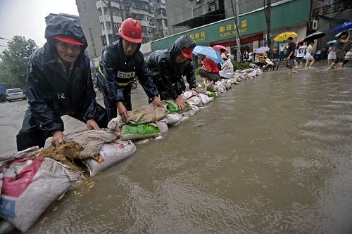 7月13日,武漢遭遇暴雨,城區(qū)積水嚴重,工作人員在江漢區(qū)一低洼處筑“壩”擋水。新華社發(fā)(王翮 攝)