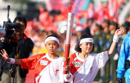 6月10日,奧運(yùn)火炬手和震生(左)與張紫蘭共同手舉火炬?zhèn)鬟f。當(dāng)日,北京奧運(yùn)圣火在云南麗江傳遞。 新華社記者邢廣利攝