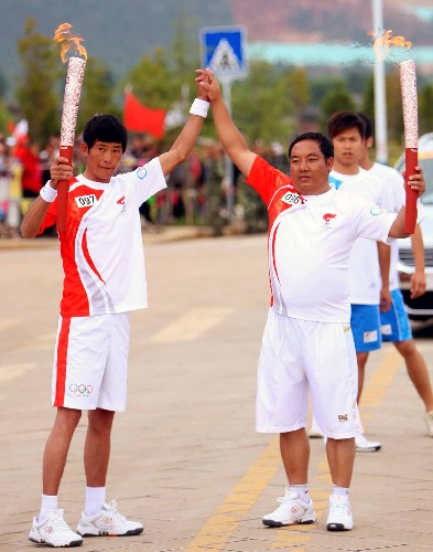 6月10日,奧運(yùn)火炬手郭正發(fā)(前右)與李爾古在傳遞過程中交接。當(dāng)日,北京奧運(yùn)圣火在云南麗江傳遞。 新華社記者邢廣利攝