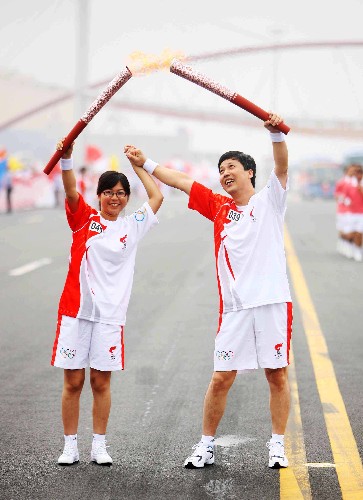 8月1日,火炬手賈瑞興(右)與尤立紅交接。當(dāng)日,北京奧運(yùn)圣火在天津市傳遞。 新華社記者邢廣利攝