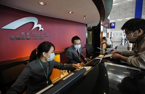 5月1日,戴著口罩的香港國際機(jī)場問詢處工作人員為旅客提供服務(wù)。新華社記者周磊攝