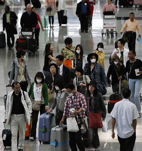 5月1日,部分戴著口罩的旅客從香港國際機(jī)場入境大堂走過。新華社記者 周磊 攝