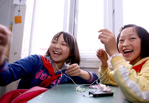 2009年4月30日,楊芹(左)在課間休息時(shí)和同學(xué)一邊聽音樂,一邊疊紙鶴。臉上、身上滿是灰塵,一雙水汪汪的大眼睛怯生生地望著——2008年5月13日上午9時(shí),在四川省綿竹市漢旺鎮(zhèn)武都小學(xué)的廢墟中,10歲的楊芹在等待救援。為了防止碎石砸傷她的頭部,救援人員給她戴上了一頂紅色的安全帽。那時(shí)起,楊芹就有了個(gè)昵稱——“小紅帽”。那頂在灰色廢墟中格外顯眼的“小紅帽”,代表著生的希望與活下去的動(dòng)力。經(jīng)歷了近20個(gè)小時(shí)的漫長等待,“小紅帽”終于被德陽消防支隊(duì)的救援人員從廢墟中抱出。然而就在楊芹所在班上,70多個(gè)孩子只有一半活了下來。 “5·12”大地震已經(jīng)過去快一年的時(shí)間,現(xiàn)在的“小紅帽”還好嗎?帶著思念與牽掛,記者驅(qū)車前往漢旺鎮(zhèn)的板房學(xué)校,探望在地震中生還的幸運(yùn)兒——“小紅帽”楊芹。從一群正在教室外的臺(tái)階上寫英語作業(yè)的孩子中,我們找到了楊芹。見到記者來,楊芹站起身,腳步蹣跚地走了過來,顯得有些羞澀。由于被埋時(shí)間過長,楊芹的右腿壞死感染,做了高位截肢手術(shù),現(xiàn)在已經(jīng)安裝了假肢。“小紅帽”特別喜歡笑,同學(xué)逗她,她馬上咯咯地樂起來,很快就恢復(fù)了開朗的本性。為了盡快擺脫地震帶來的陰影,現(xiàn)在的楊芹每周都