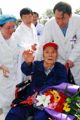 6月11日,來自什邡地震災區(qū)91歲高齡的張榮芳老人出院時與煙臺市毓璜頂醫(yī)院的醫(yī)護人員揮手告別。新華社發(fā)(申吉忠 攝)