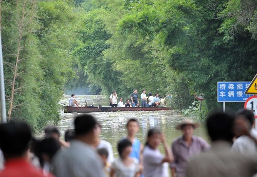 6月14日,在廣西梧州市長洲區(qū)倒水鎮(zhèn),人們乘船從被水淹沒的公路上通過。新華社記者 周華 攝
