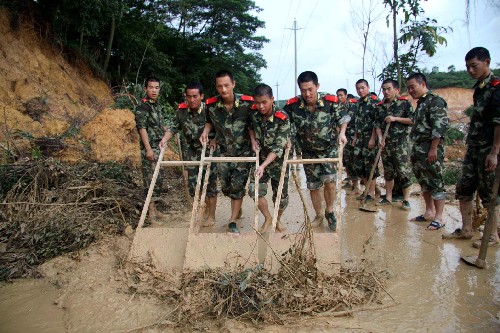 6月14日,深圳邊防支隊輪訓(xùn)隊的官兵在寶安區(qū)章閣村路段清理塌方的淤泥。新華社記者 周文杰 攝