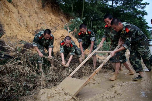 6月14日,深圳邊防支隊輪訓(xùn)隊的官兵在寶安區(qū)章閣村路段清理塌方的淤泥。新華社記者 周文杰 攝