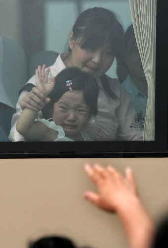 6月17日,在天津大禮堂門前舉行的歡送儀式上,4歲的小傷員孫麗和母親一起向醫(yī)護(hù)人員揮手告別。新華社發(fā)(趙建偉 攝)