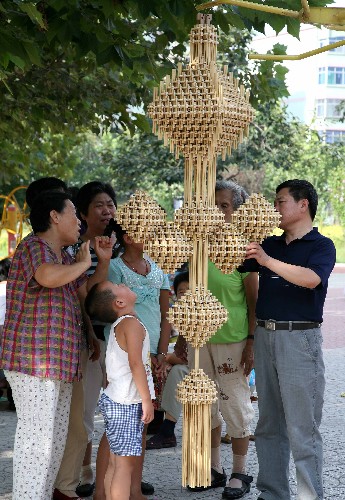 8月23日,天津市民李寶岐(右)向人們介紹自己用秸稈扎制的奧運中國結(jié)。新華社發(fā)(任麗華 攝)