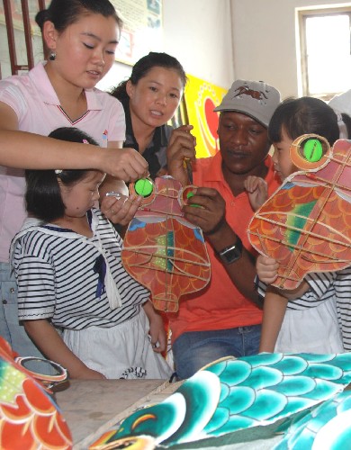 9月7日,山東濰坊奎文外國語幼兒園的外籍教師和幼兒園小朋友在中國老師的指導(dǎo)下學(xué)習(xí)扎制風(fēng)箏。新華社發(fā)(王立軍 攝)