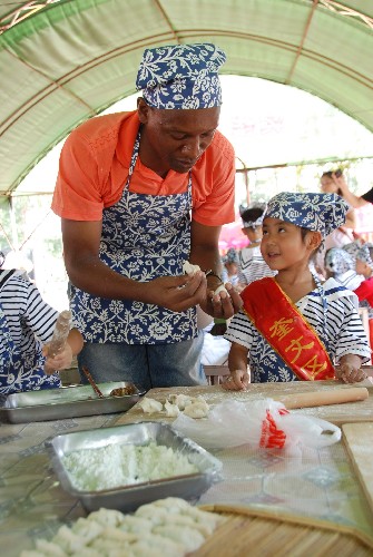 9月7日,山東濰坊奎文外國語幼兒園的外籍教師在幼兒園小朋友的“指導(dǎo)”下學(xué)包水餃。新華社發(fā)(王立軍 攝)