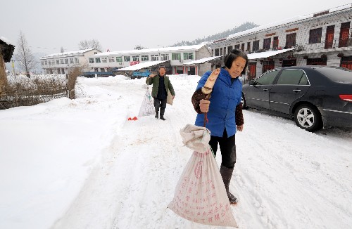 霍山縣朱佛庵鎮(zhèn)兩位居民挑著剛打的糧食回家(1月30日攝)。新華社記者 陳曄華 攝
