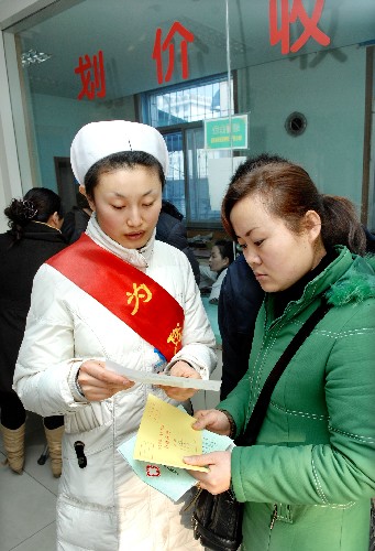 2月14日,玉皇閣北街社區(qū)衛(wèi)生服務(wù)中心的導(dǎo)醫(yī)護(hù)士在介紹收費(fèi)下調(diào)藥品目錄。新華社記者 李紫恒 攝