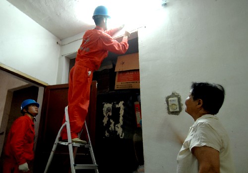 7月15日,搶修隊員主動上門服務,在嘉興市真合社區(qū)70多歲的居民余文英(右)家檢修線路。 浙江嘉興市南湖區(qū)供電分局“紅船”電力搶修服務隊,為確保群眾不因線路故障影響觀看奧運賽事,推出多項新舉措,實現(xiàn)故障搶修平均到位時間23分鐘,并積極服務弱勢群體,免費為城市困難家庭提供電力服務,受到群眾好評。 新華社記者 黃深鋼攝