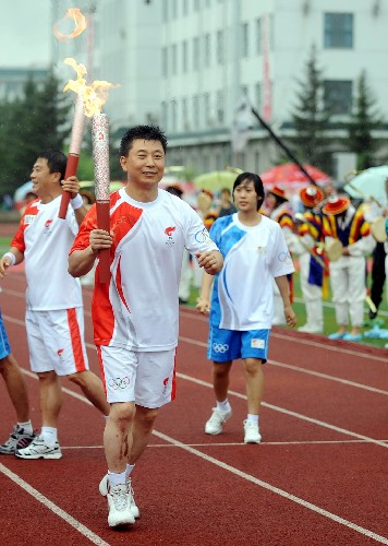 7月16日,火炬手杜運(yùn)起(中)手持火炬進(jìn)行傳遞。當(dāng)日,北京奧運(yùn)圣火在延吉市傳遞。 新華社記者王昊飛攝