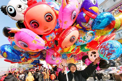 1月26日,一名商販?zhǔn)殖治宀世_紛的氣球在江蘇贛榆縣城市場(chǎng)兜售。新華社發(fā)(司偉 攝)