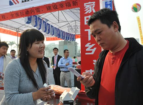 2月10日,在廣州市番禺區(qū)舉行的“家電下鄉(xiāng)”促銷活動中,銷售人員(左)在向一位農(nóng)民介紹一款手機。新華社記者 壯錦 攝