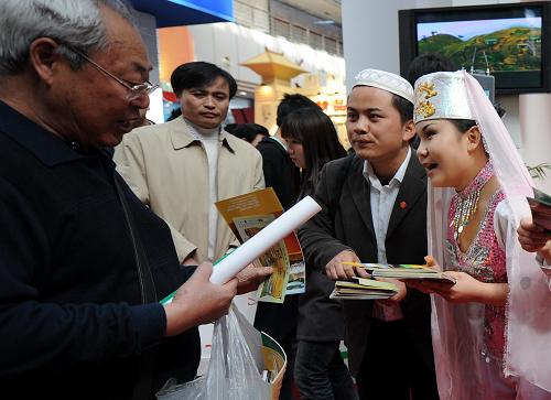 4月5日,寧夏展臺(tái)工作人員(右一、右二)身著民族服裝向客商發(fā)放資料。 新華社記者 焦衛(wèi)平 攝