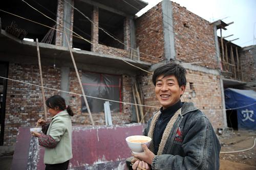 2008年11月21日,感恩村村民李旭德在自家在建的房屋前。