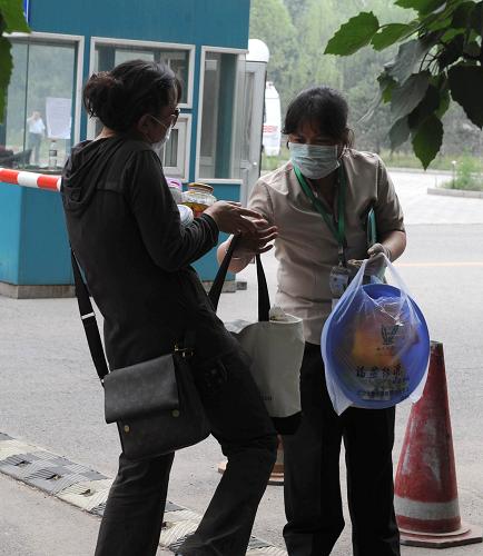 5月11日,被隔離者的親友(左)把送來的日常用品交給隔離地的服務(wù)員。新華社記者 李文 攝