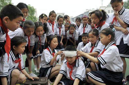 5月11日,在宜昌市萬壽橋小學(xué)舉行的一場應(yīng)急演練活動中,學(xué)生們在為“傷員”包扎。 當(dāng)日,為紀(jì)念汶川地震一周年和迎接5月12日我國首個“防災(zāi)減災(zāi)日”,湖北省宜昌市萬壽橋小學(xué)開展“抗震救災(zāi)自救自護(hù)技能演練”活動,全校700多名學(xué)生參加了現(xiàn)場救護(hù)、地震避難、逃生等項目的演練。新華社發(fā)(黃翔 攝)