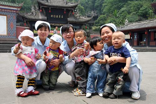 5月11日,三名護(hù)士王麗(左二)、羅云莉(左四)和張?zhí)m(右二)在曾經(jīng)護(hù)理過“地震寶寶”的廣場上與5名嬰兒合影。 新華社記者 鄭悅 攝