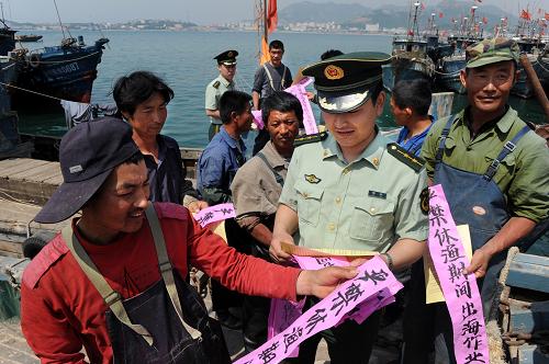 5月31日,青島沙子口公安邊防派出所警官在漁港內(nèi)向漁民進行休漁宣傳。2009年黃渤海伏季休漁時間調(diào)整為6月1日12時至9月16日12時,較往年提前了半個月。目前黃渤海沿岸漁船紛紛回港停泊,為海洋生物提供休養(yǎng)生息時間,促進海洋漁業(yè)資源的可持續(xù)利用。 新華社記者 李紫恒 攝