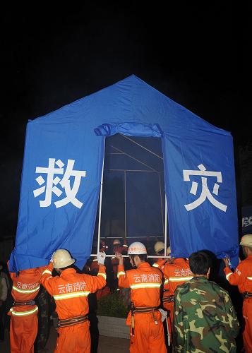7月10日凌晨,消防官兵在云南省楚雄彝族自治州姚安縣官屯鄉(xiāng)官屯村為震區(qū)群眾搭建好帳篷后準(zhǔn)備抬到平地上。 新華社記者 藺以光 攝