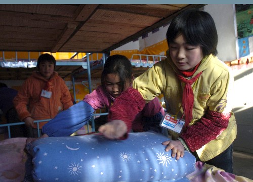 1月4日,金塔縣古城小學(xué)六年級四班的王海霞(右)在宿舍里整理被褥。