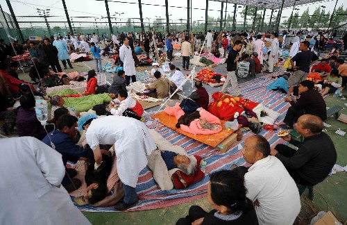 目擊綿竹災(zāi)區(qū)救援 5月13日,在四川綿竹縣的一處臨時(shí)救援中心,醫(yī)務(wù)人員在醫(yī)治傷員。 新華社記者 李曉果 攝