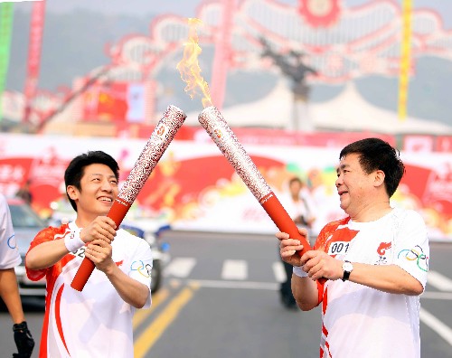 5月25日,火炬手孫志安(右)與火炬手撒貝寧交接。當(dāng)日,北京奧運(yùn)會(huì)圣火在江蘇蘇州傳遞。 新華社記者邢廣利攝