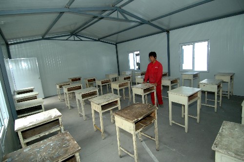 陜西災區(qū)有了高考“活動考場” 6月4日,工人在活動板房內(nèi)安置書桌。 經(jīng)有關方面人員連續(xù)幾天的奮戰(zhàn),陜西漢中市地震災區(qū)寧強縣、略陽縣已搭建完成了112間防震活動板房,兩縣3045名學生將在這些“活動考場”中如期參加高考。 新華社記者丁海濤攝