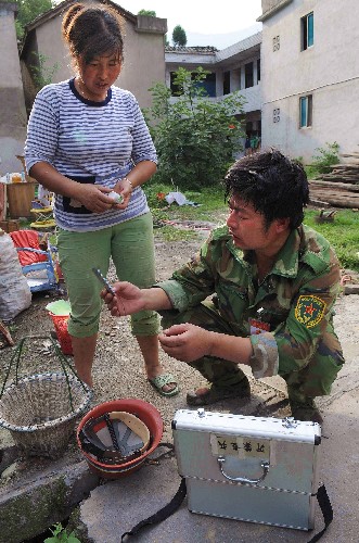 7月1日,曾做過衛(wèi)生兵的沂蒙老兵志愿者姚文善(右)在給當(dāng)?shù)鼐用癜l(fā)藥。
