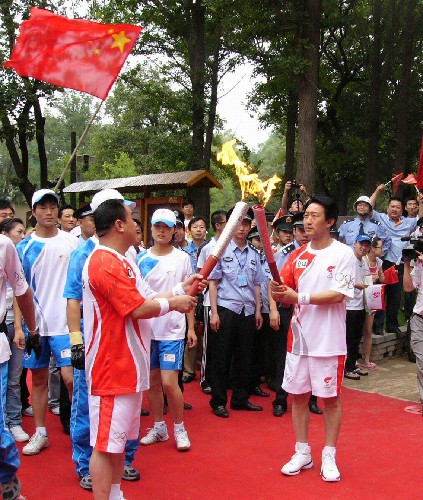 奧運圣火在延安傳遞 7月2日,火炬手劉森民(前右)在棗園舊址與火炬手馮世陽進行交接。當(dāng)日,北京奧運會圣火在延安傳遞。 新華社記者丁靜攝