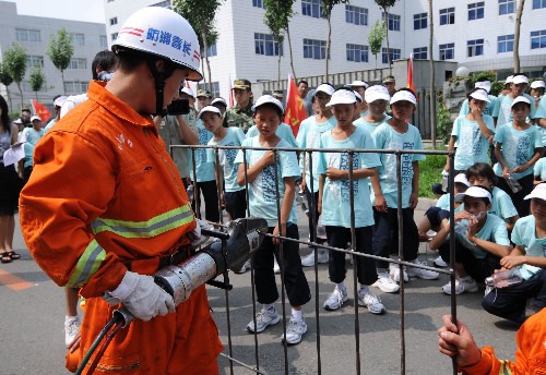 7月27日,孩子們在觀看消防人員演示救援工具的使用方法。