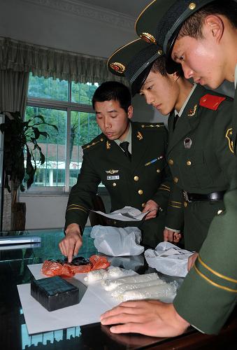 云南木康公安邊防檢查站的官兵正在查看繳獲的海洛因和冰毒(12月24日攝)。