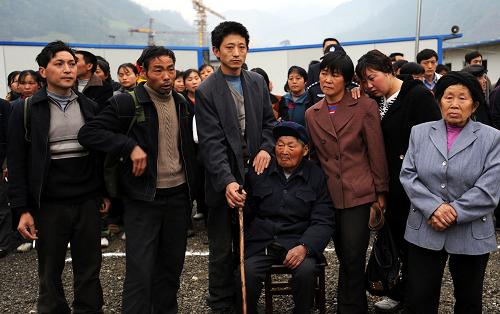 月27日,85歲的羅得清老人(右四)和家人在離開青川縣關莊鎮(zhèn)寺壩板房區(qū)前合影留念。