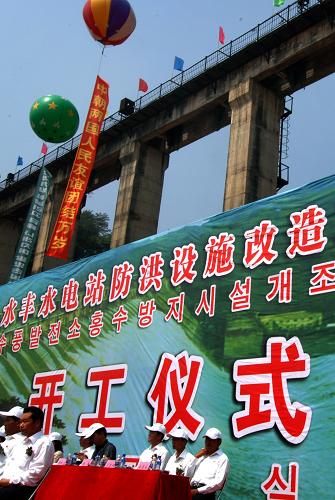 圖為8月15日拍攝的開(kāi)工儀式現(xiàn)場(chǎng)。當(dāng)日,中朝界河上最大一座水電站——水豐水電站防洪設(shè)施改造工程開(kāi)工儀式在遼寧丹東舉行。這座運(yùn)行近70年的鴨綠江上最大一座水電站的大壩,將全面進(jìn)行除險(xiǎn)加固。水豐水電站是中朝界河鴨綠江上現(xiàn)有四座水電站中的最早也是最大一座,水庫(kù)庫(kù)容147億立方米。經(jīng)過(guò)近70年的運(yùn)行,大壩、防洪和發(fā)電設(shè)備等存在嚴(yán)重安全隱患。此次改造工程將對(duì)水豐水庫(kù)主壩、副壩的數(shù)十座防洪閘門及其輔助設(shè)施進(jìn)行更新改造。新華社記者 姚劍鋒 攝