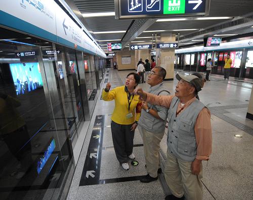 9月28日,地鐵四號線的車站助理(左一)正在為乘客解答關(guān)于換乘的問題。
