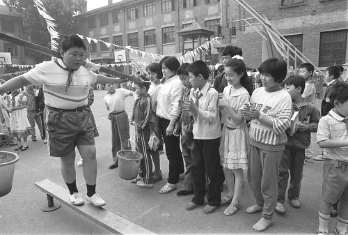 1991年“六一”兒童節(jié),北京第二實(shí)驗(yàn)小學(xué)舉辦主題為“到宇宙去旅行”的科學(xué)城游樂活動(dòng)。挑水過獨(dú)木橋的游戲最吸引小朋友。這些肩膀從未接觸過扁擔(dān)的兒童都爭(zhēng)相一試。這位110斤的小胖子在伙伴掌聲的鼓勵(lì)下正咬緊牙關(guān)過橋。 新華社記者張燕輝攝 (資料照片)