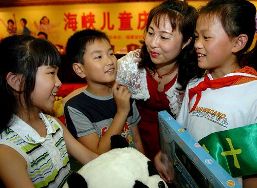 2005年5月28日,在海峽兒童“慶‘六一’話成長”活動上,跟隨經(jīng)商父母在福州上學(xué)的臺灣兒童王雯(左一)和林昕宏(左二)與來自貧困山區(qū)的春蕾女童福建省永春縣文溪小學(xué)四年級學(xué)生曾雅鳳互贈節(jié)日禮物。 新華社記者張國俊攝(資料照片)